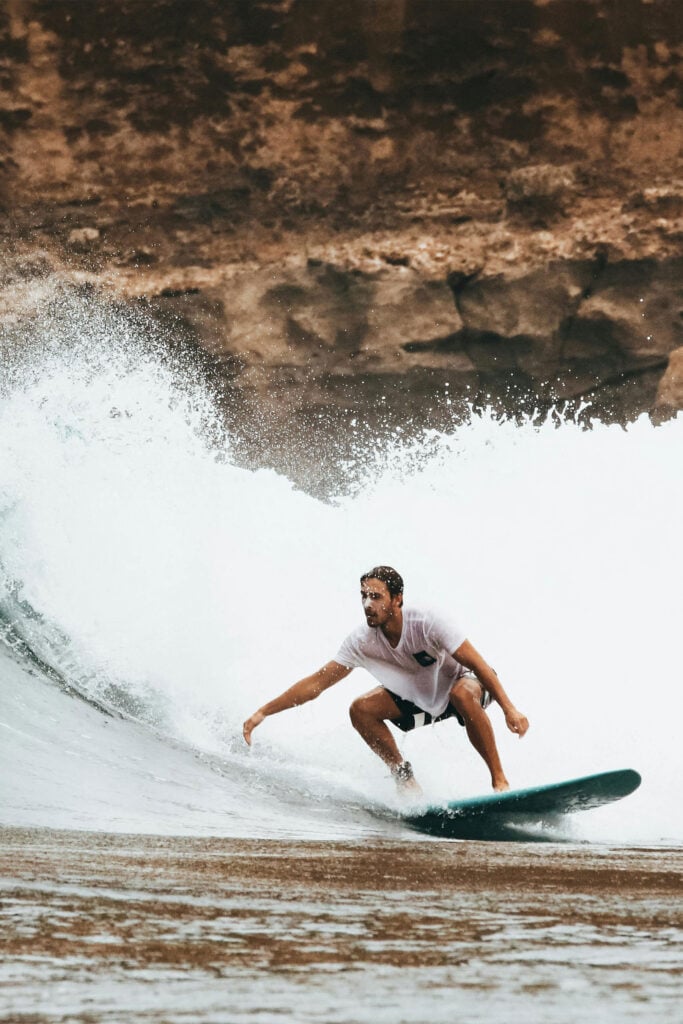 Traveler surfing along a rugged coastline during an outdoor adventure getaway