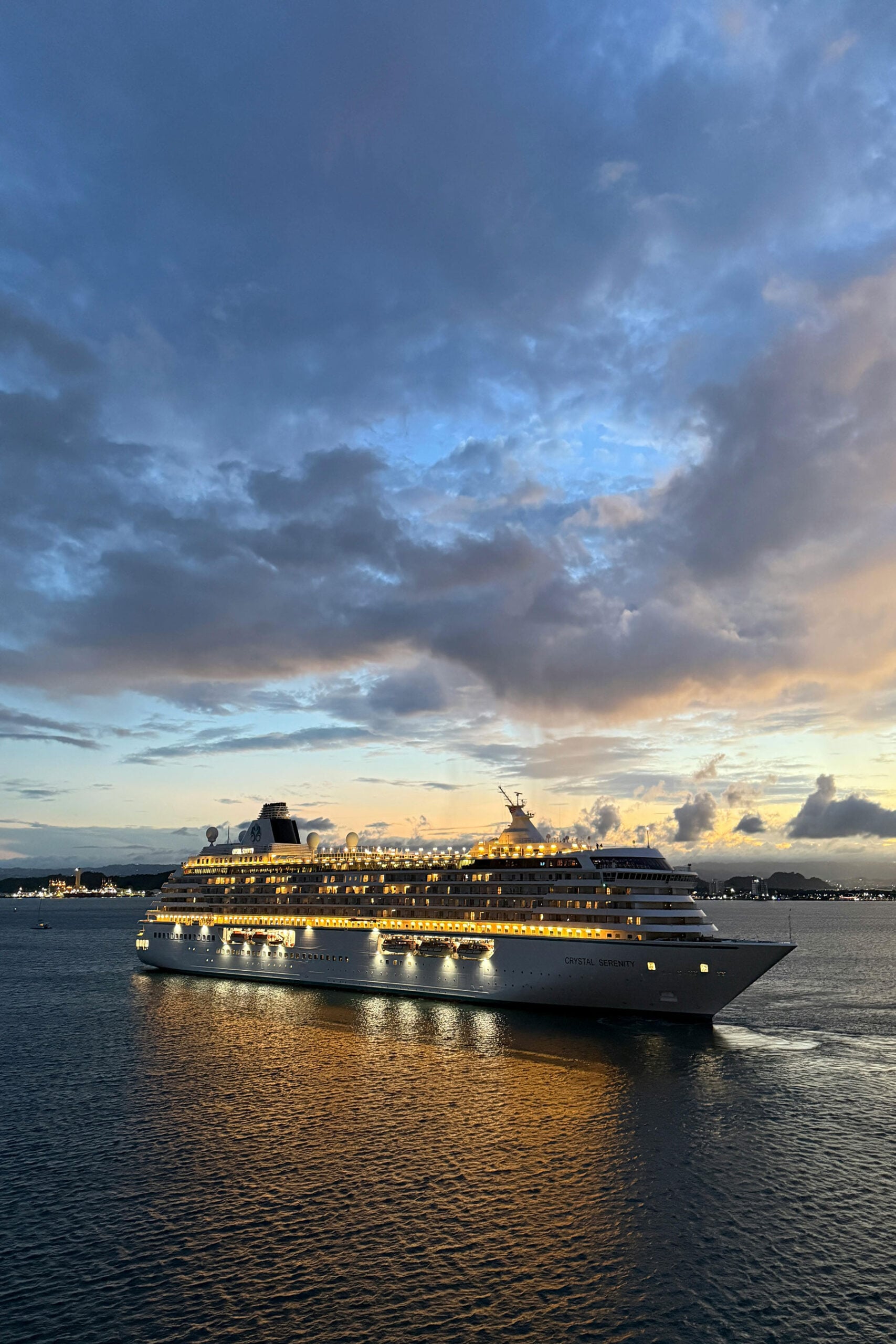 Cruise ship illuminated at dusk beneath dramatic clouds