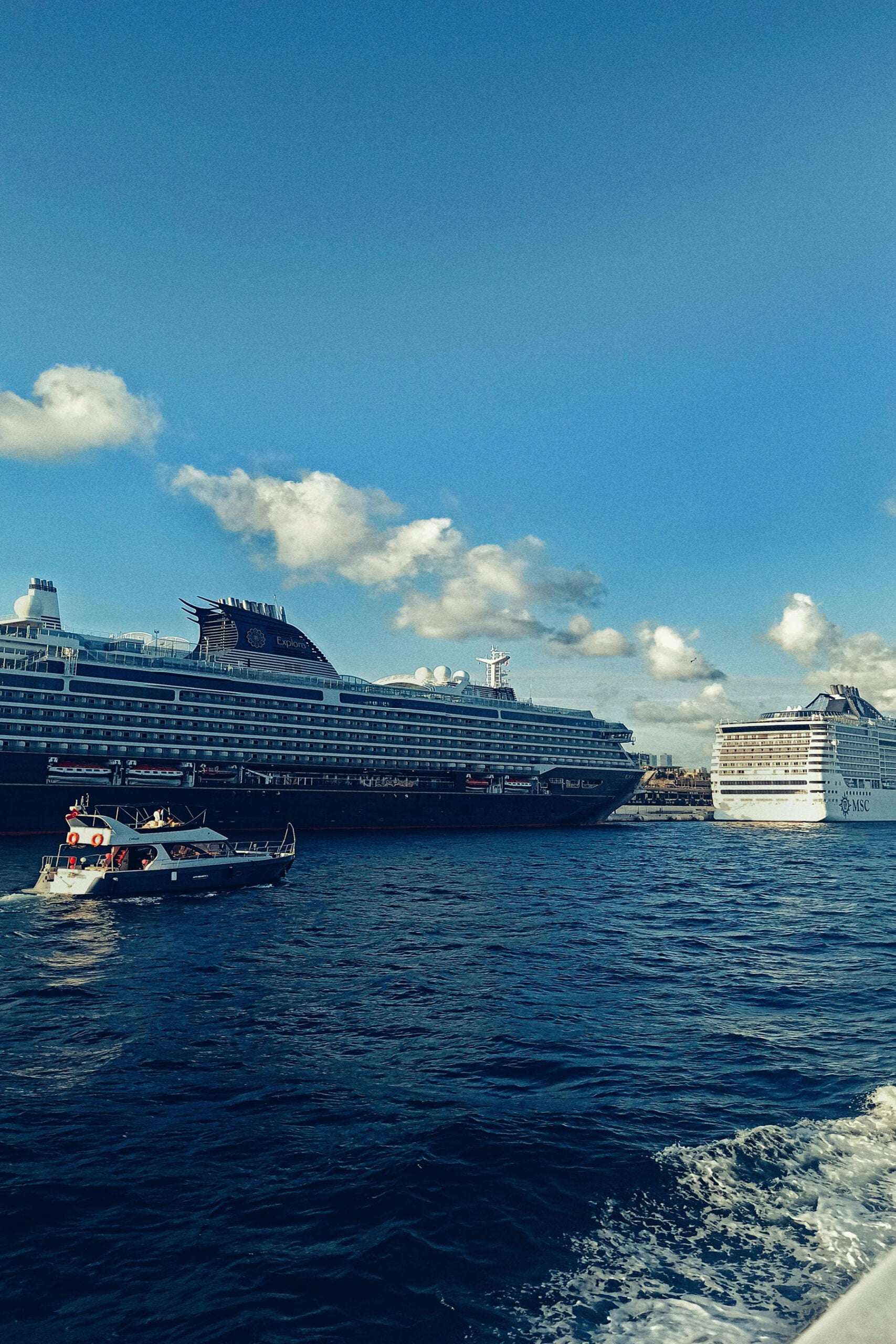 Cruise ship docked near harbor with smaller boats on the water