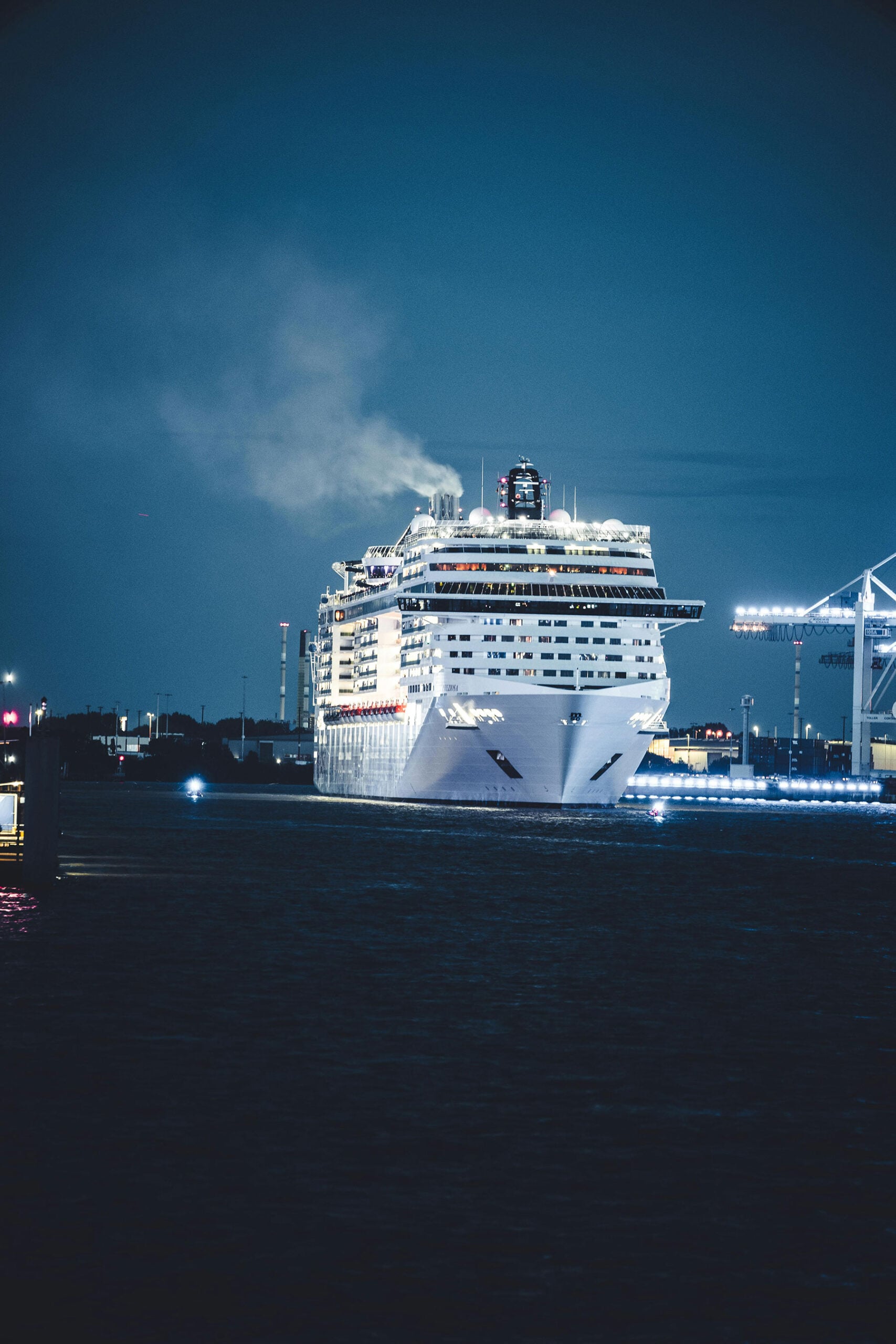 Illuminated cruise ship arriving at port at night