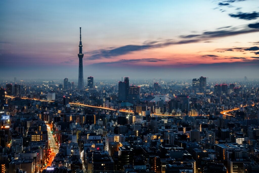 Tokyo skyline at sunset featuring Tokyo Skytree rising above the illuminated cityscape.