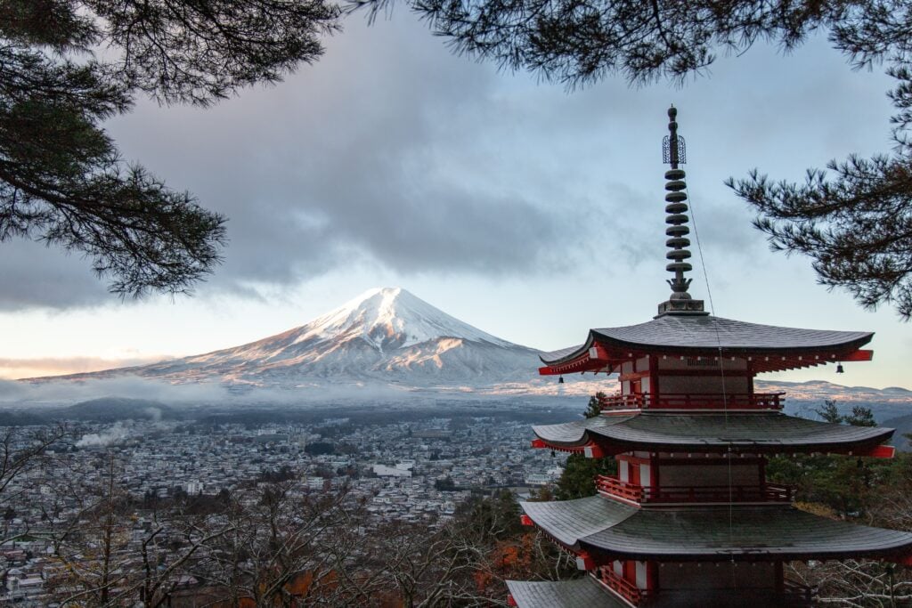 Chureito Pagoda overlooking Mount Fuji with cherry blossoms and dramatic clouds in Japan.