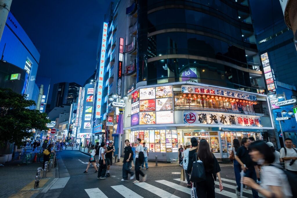 Bright neon lights and busy streets in Shibuya's entertainment district after dark in Tokyo
